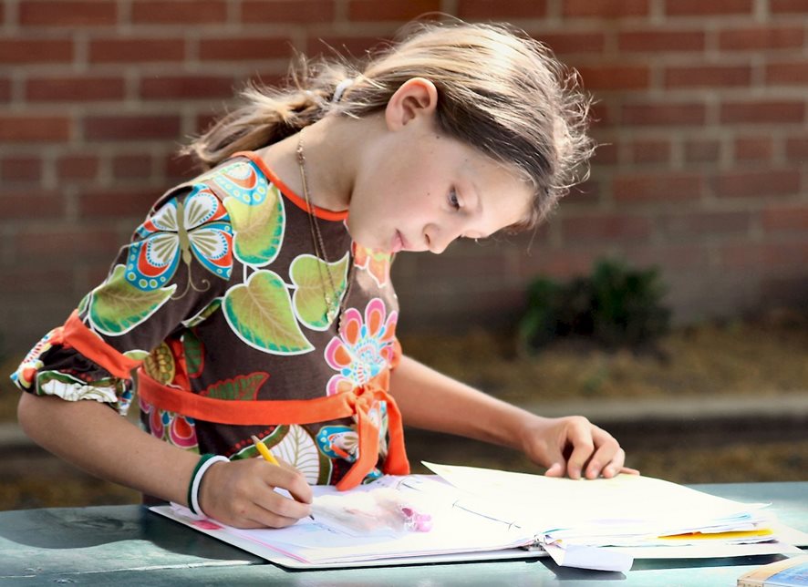 Girl writing in primary workbook